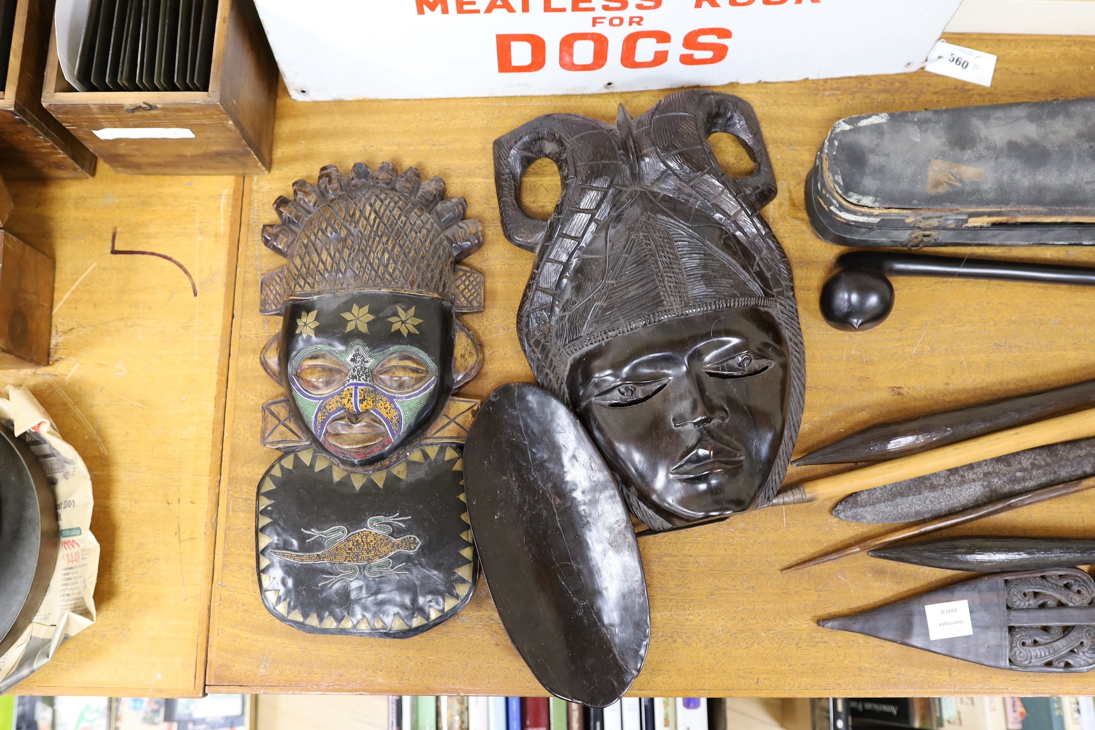 A selection of clubs and weapons to include a knobkerry, together with tribal masks